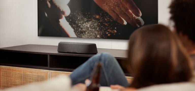 Woman watching tv with a compact sound bar.